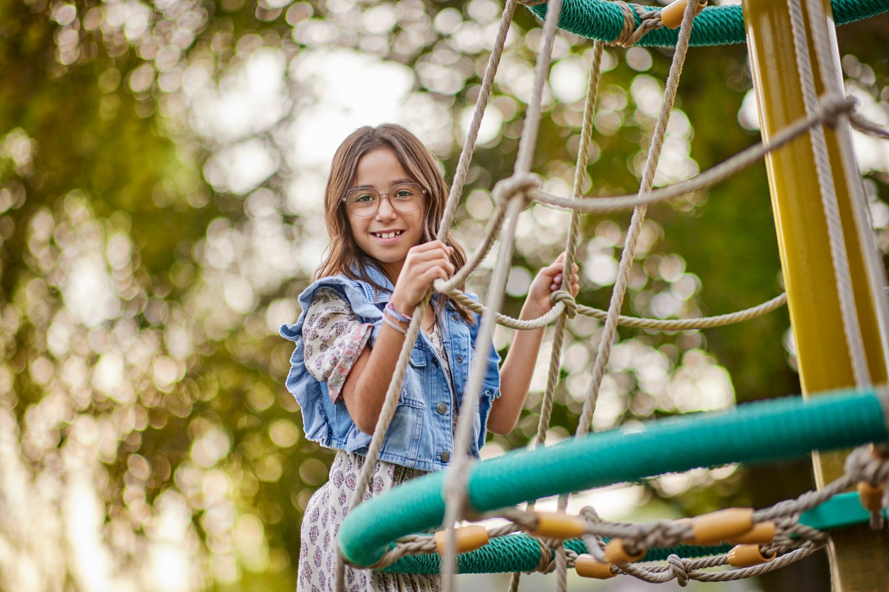 Kinderbrillen – Ein Kind spielt fröhlich auf einem Spielplatz und sieht uns an.